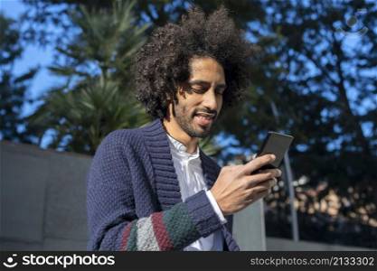 Portrait of handsome afro man using his mobile in the street.