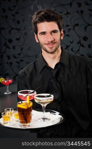 Portrait of handsome barman at bar holding tray with cocktails