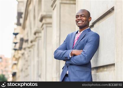 Portrait of handsome black man wearing suit, smiling in urban background