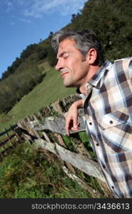 Portrait of handsome breeder leaning on fence