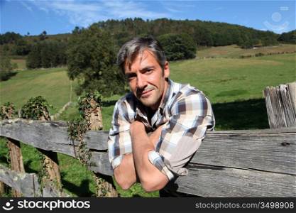 Portrait of handsome breeder leaning on fence