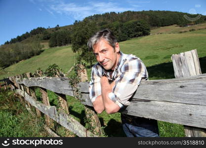 Portrait of handsome breeder leaning on fence