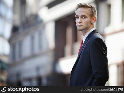 Portrait of handsome businessman in suit standing against building