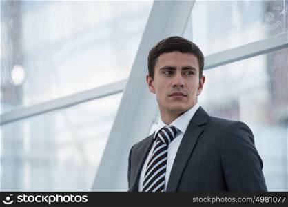 Portrait of handsome confident young businessman standing relaxed, smiling happy, looking away