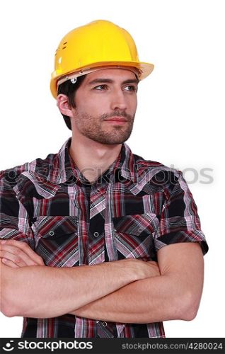 portrait of handsome craftsman with safety helmet standing cross-armed
