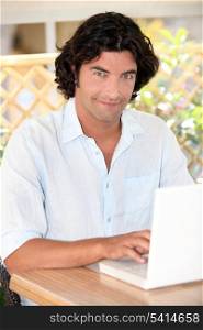 portrait of handsome dark-haired man working on laptop
