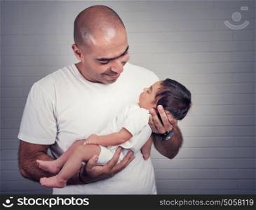 Portrait of handsome father holding on hands cute little baby, spending time at home, lovely young family, love and happiness concept