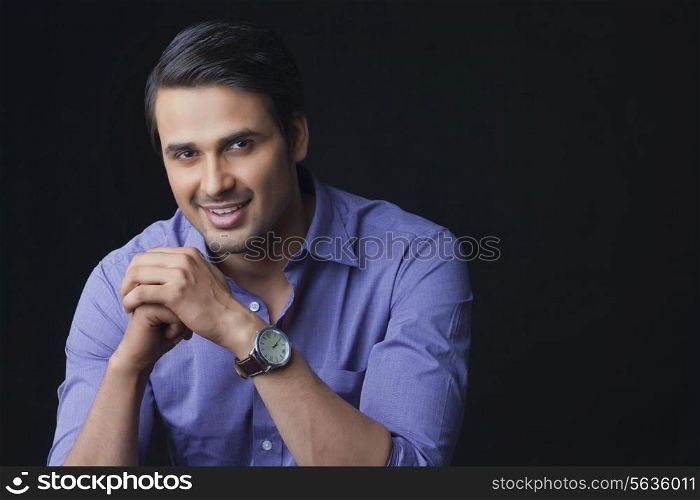 Portrait of handsome Indian businessman smiling over black background