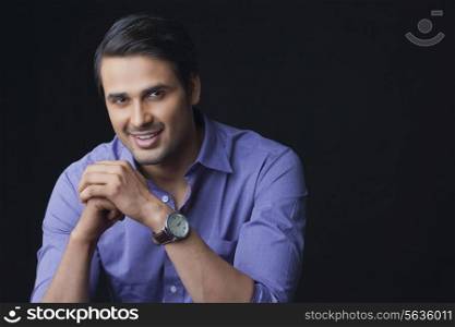 Portrait of handsome Indian businessman smiling over black background