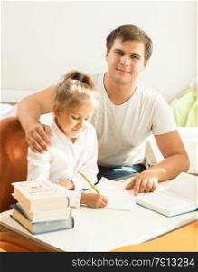 Portrait of handsome man helping daughter with homework