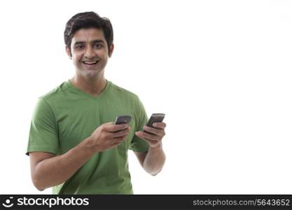 Portrait of handsome man holding cell phones over white background