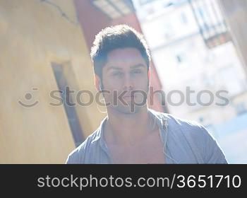 Portrait of handsome man in urban background listening to the music with headphones