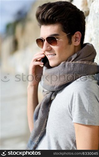 Portrait of handsome man in urban background talking on phone