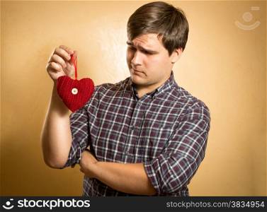 Portrait of handsome man looking suspiciously on decorative red heart