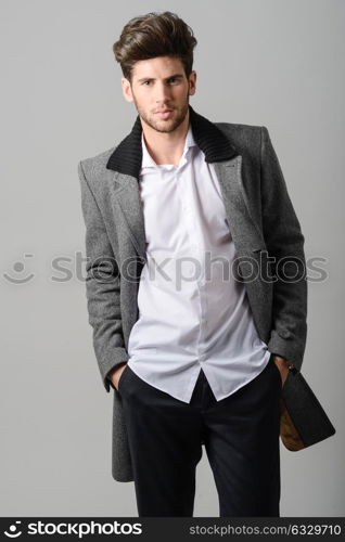 Portrait of handsome man, model of fashion, wearing coat. Studio shot