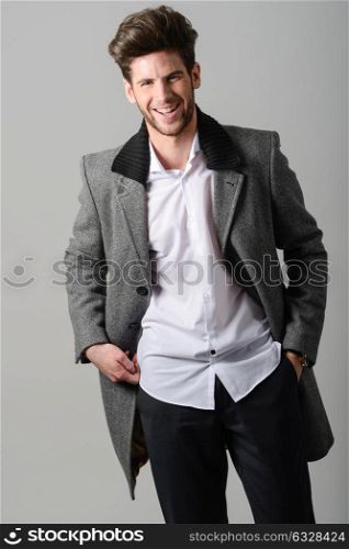 Portrait of handsome man smiling, model of fashion, wearing coat. Studio shot