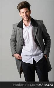 Portrait of handsome man smiling, model of fashion, wearing coat. Studio shot