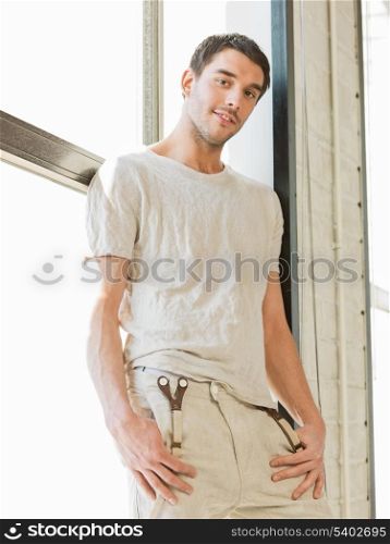 portrait of handsome man standing on the windowsill