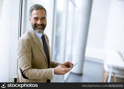 Portrait of handsome mature businessman with digital tablet in the modern office