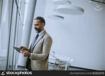 Portrait of handsome mature businessman with digital tablet in the modern office