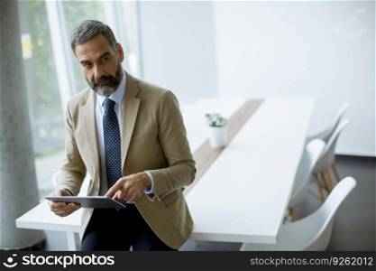 Portrait of handsome mature businessman with digital tablet in the modern office