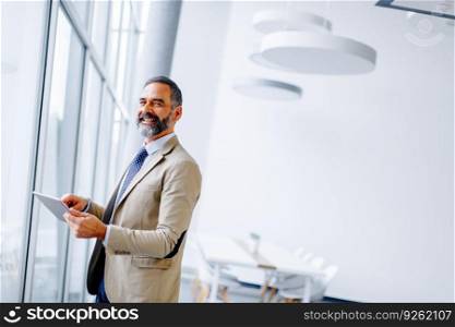 Portrait of handsome mature businessman with digital tablet in the office