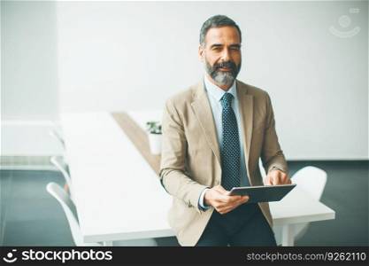 Portrait of handsome mature businessman with digital tablet in the office