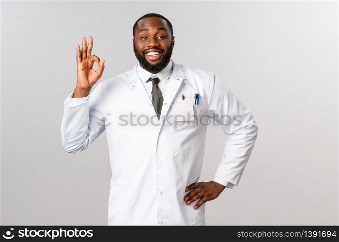 Portrait of handsome optimistic african-american male doctor guarantee you be fine during coronavirus oubreak pandemic if staying home, social-distancing and avoiding crowd places, show ok sign.. Portrait of handsome optimistic african-american male doctor guarantee you be fine during coronavirus oubreak pandemic if staying home, social-distancing and avoiding crowd places, show ok sign
