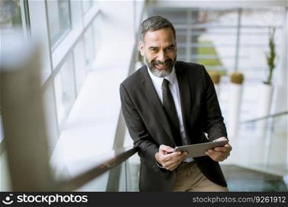 Portrait of handsome senior businessman with digital tablet in the modren office