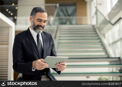 Portrait of handsome senior businessman with digital tablet in the modren office