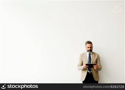 Portrait of handsome senior businessman with tablet by wall