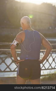 portrait of handsome senior jogging man while relaxing and take break after morning run