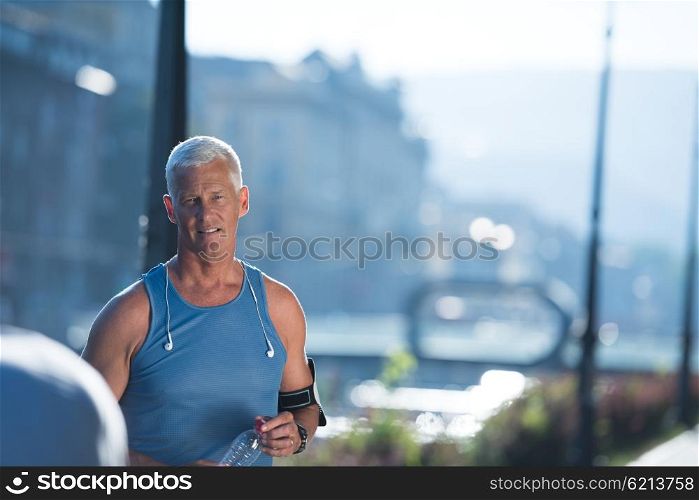 portrait of handsome senior jogging man while relaxing and take break after morning run