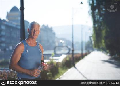 portrait of handsome senior jogging man while relaxing and take break after morning run
