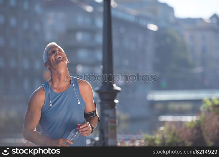 portrait of handsome senior jogging man while relaxing and take break after morning run