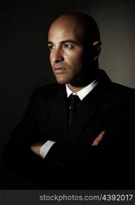 Portrait of handsome serious man wearing black stylish suit isolated on dark background, successful businessman