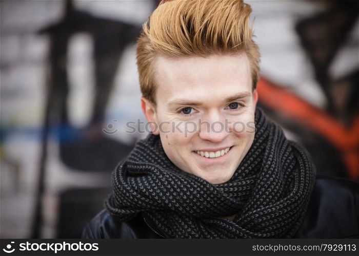 Portrait of handsome trendy man outdoor in city setting, male model stylish haircut against graffiti wall