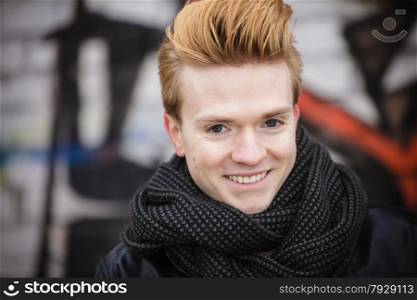 Portrait of handsome trendy man outdoor in city setting, male model stylish haircut against graffiti wall