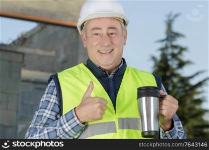 portrait of handsome worker in helmet having coffee break