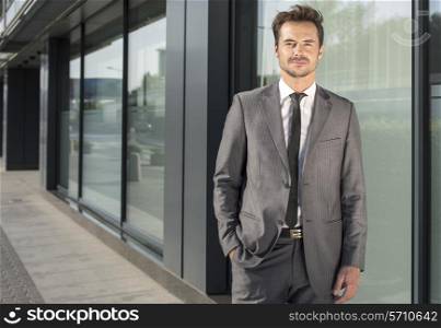 Portrait of handsome young businessman standing outside office building