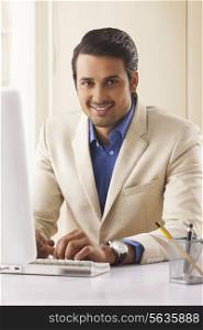 Portrait of handsome young businessman using computer in office