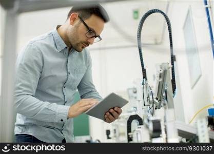 Portrait of handsome young man in the electronic workshop using digital tablet