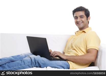 Portrait of handsome young man on sofa using laptop