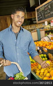 Portrait of handsome young man shopping for fruits in market