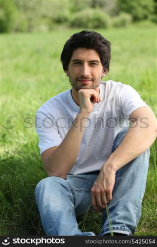 portrait of handsome young man sitting on grass