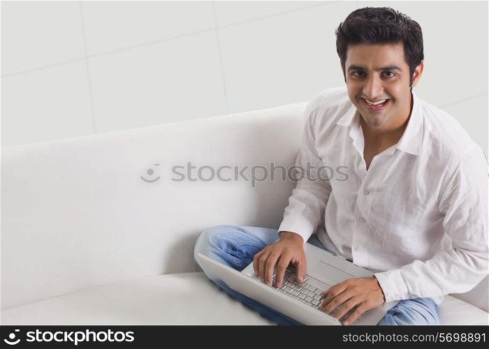 Portrait of handsome young man using laptop , smiling