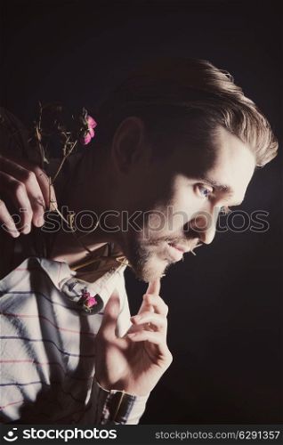 Portrait of handsome young man with dry flowers on black background