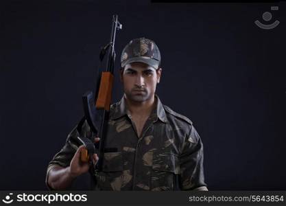 Portrait of handsome young military soldier holding gun