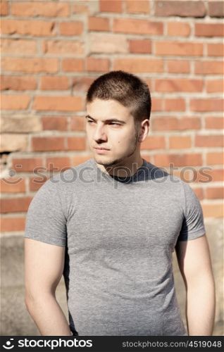 Portrait of handsome young muscular man in front of brick wall