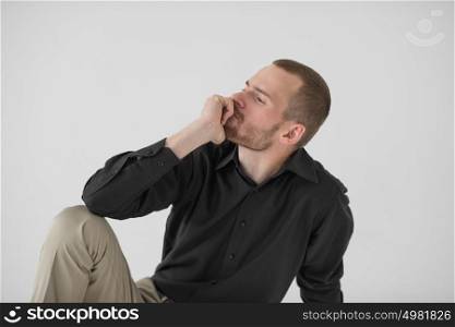 Portrait of handsome young thoughtful man sitting on white background